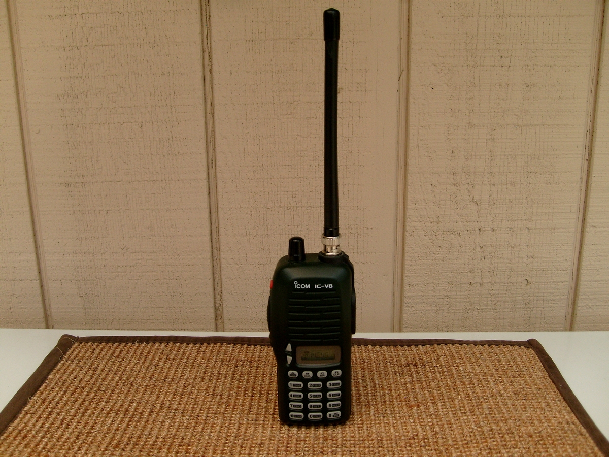 A black Icom IC-V8 handheld VHF amateur radio transceiver with its antenna extended
